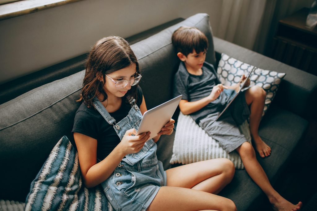 Niños en un sofá utilizando las mejores apps para aprender programación
