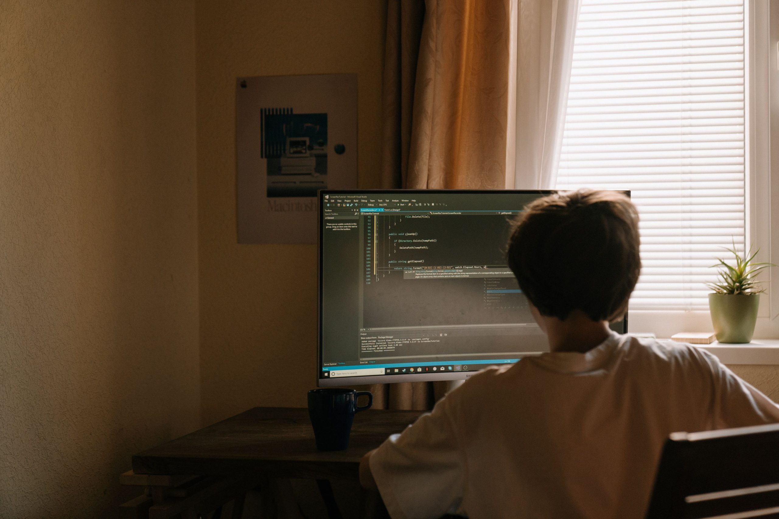 Programación de alto nivel: niño de espaldas programando en una pantalla de ordenador con código de texto. Lenguajes de programación.