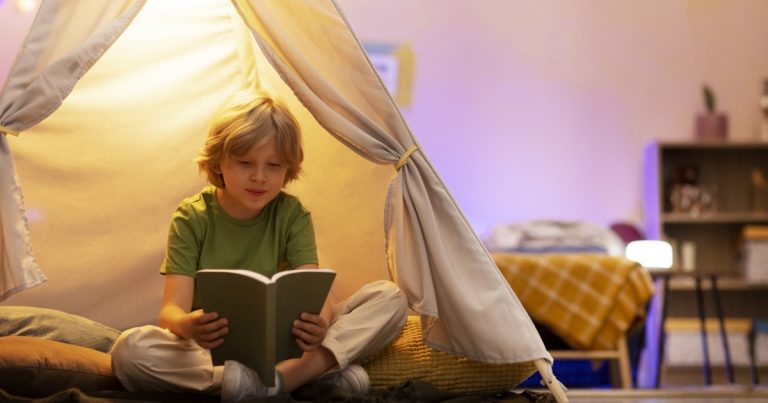 Tipos de lectores. Niño de 6–10 años leyendo un libro en casa, con expresión concentrada o de descubrimiento.
